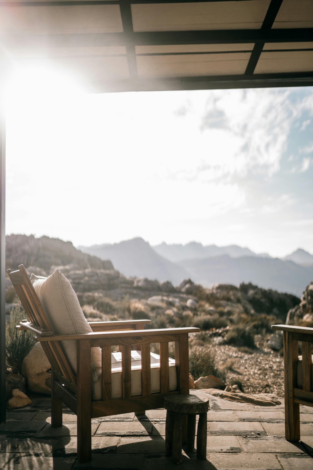 Luxueuze lodge met houten fauteuil en uitzicht op de bergen bij zonsondergang